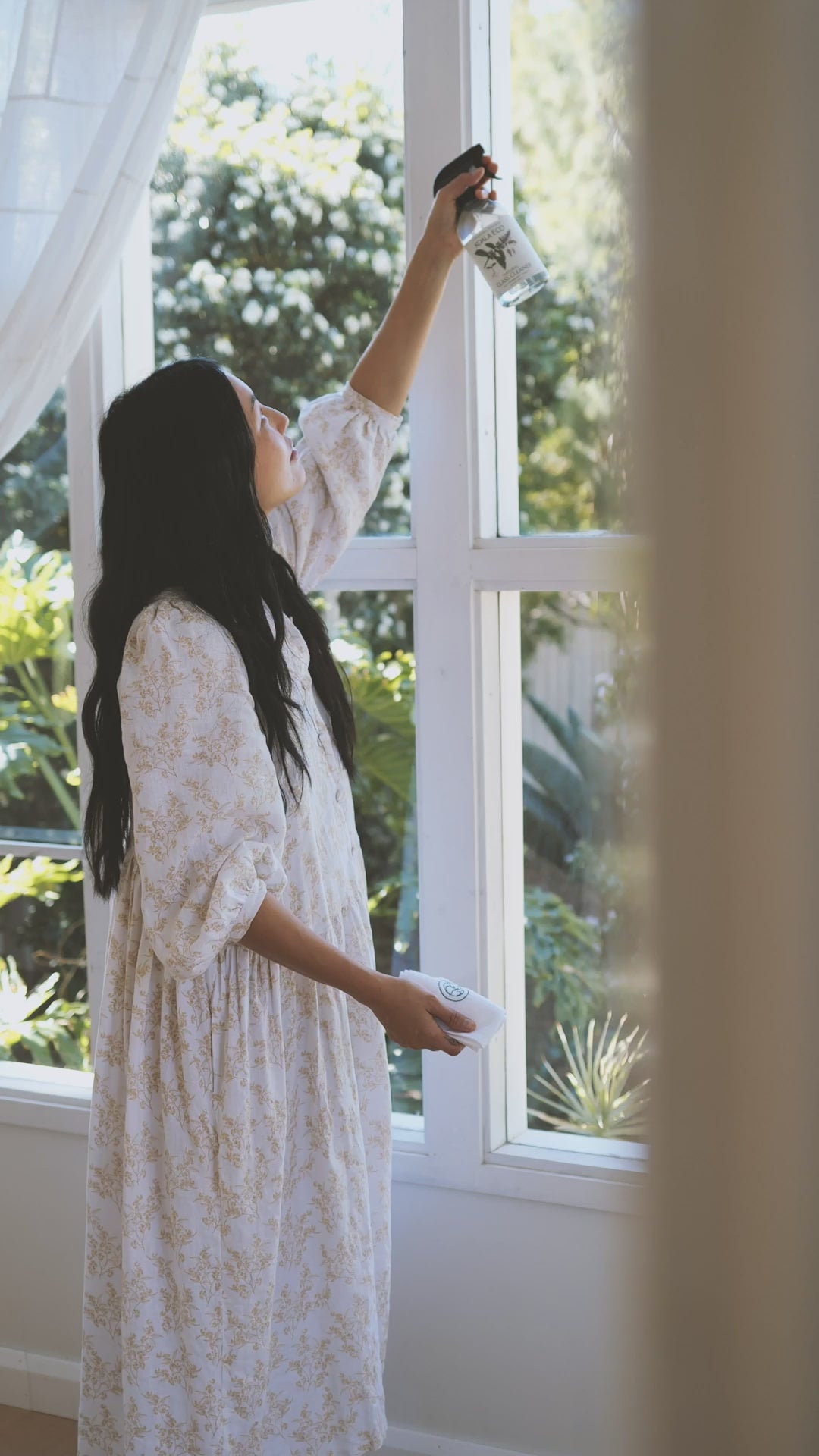 A woman washing windows with koala Eco glass cleaner